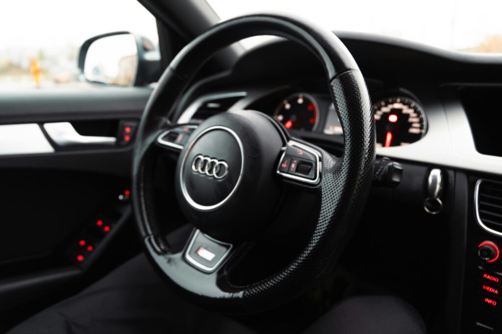 Close-up of luxury car steering wheel with dashboard and interior details, emphasizing elegance and comfort.